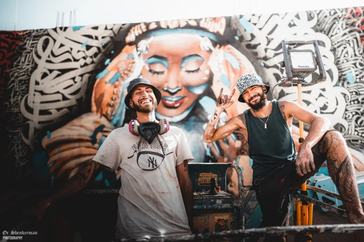 The two artists in front of the mural